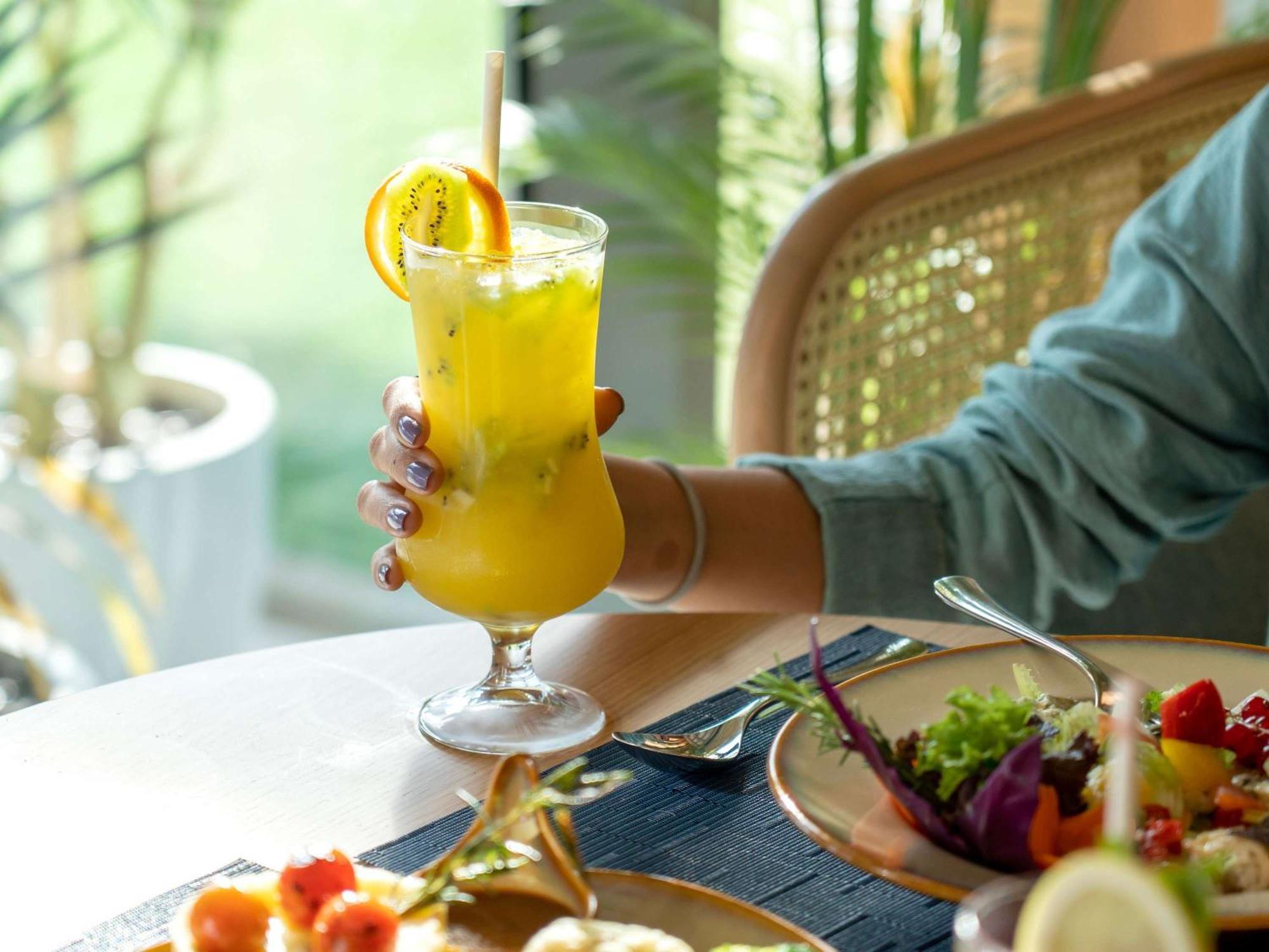 Swissotel Living Jeddah Bagian luar foto A woman holding a glass of juice